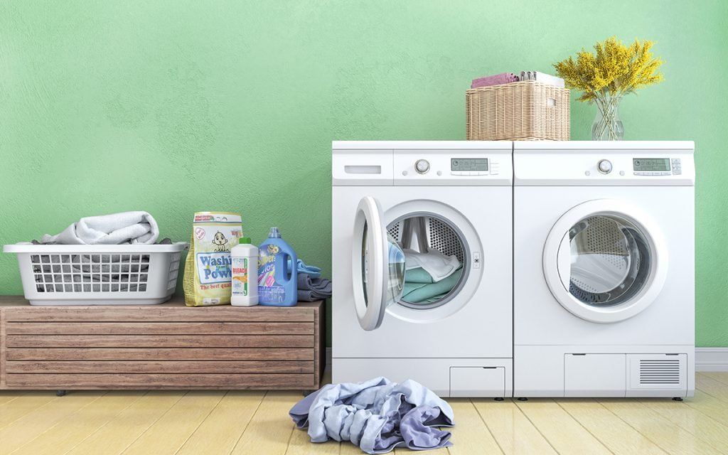 A laundry room with two washing machines and a basket of clothes.