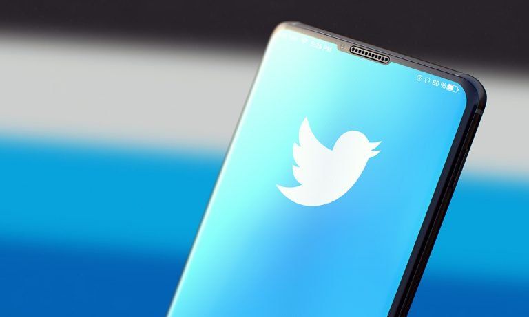 A close up of a cell phone with a twitter logo on the screen