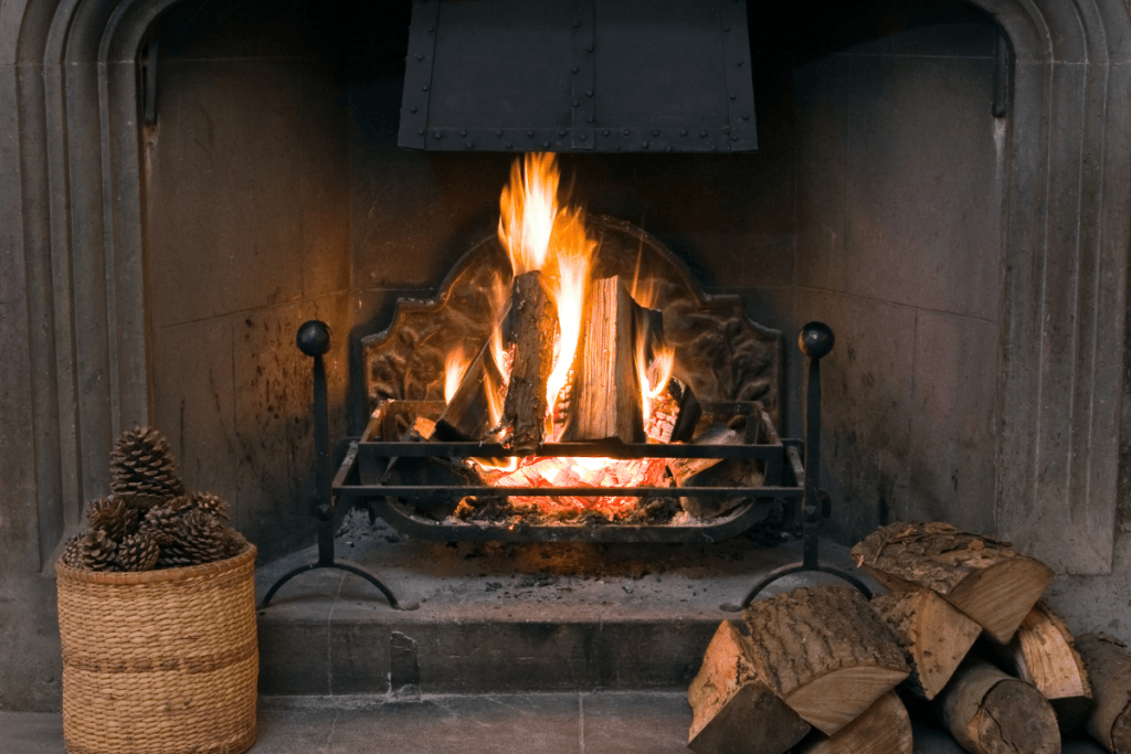 A fireplace with a basket of pine cones next to it