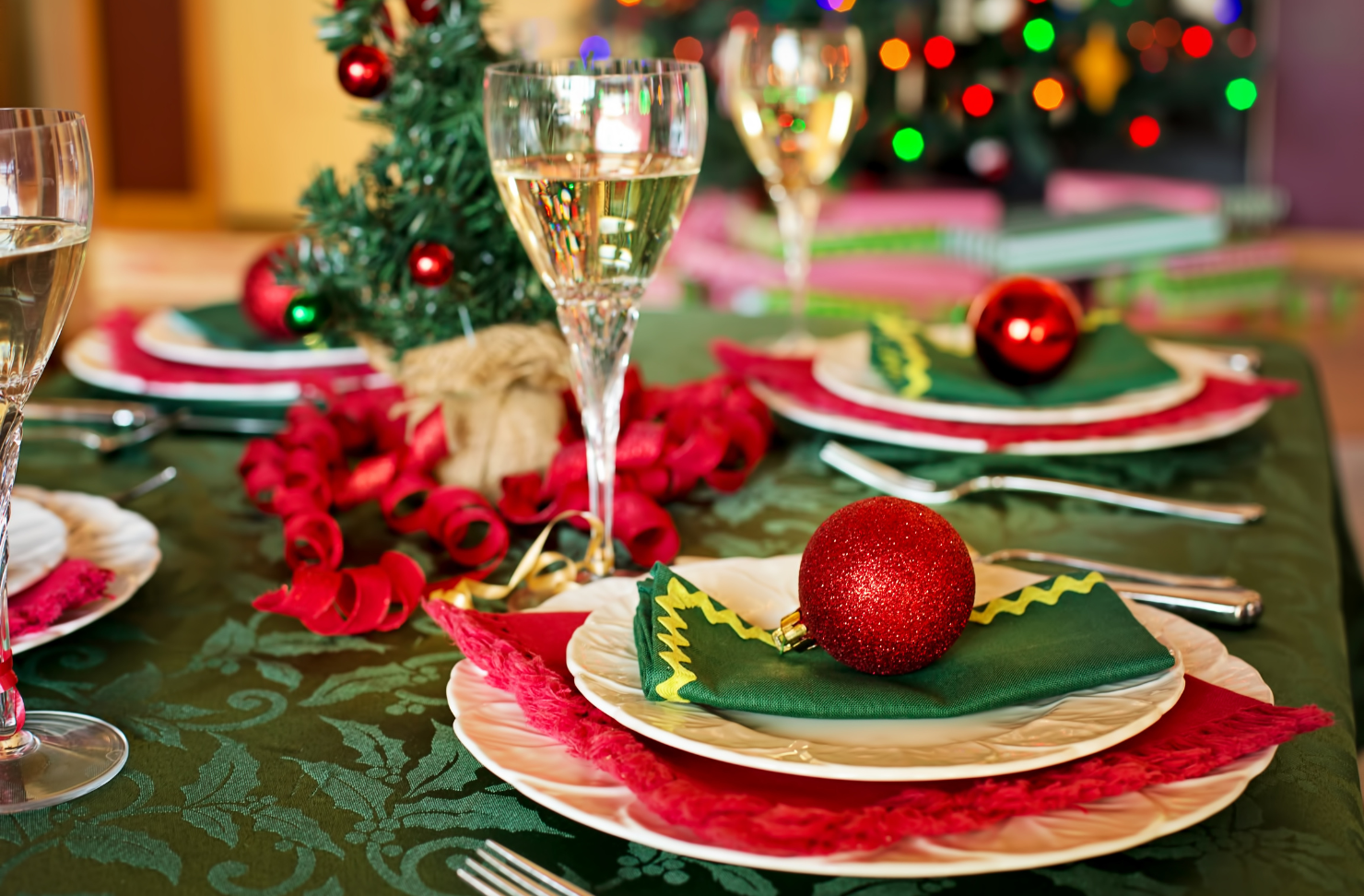 A table set for a christmas dinner with plates and wine glasses