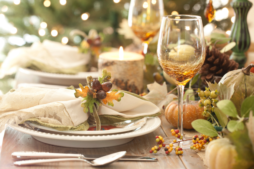 A table set for a thanksgiving dinner with plates utensils and wine glasses