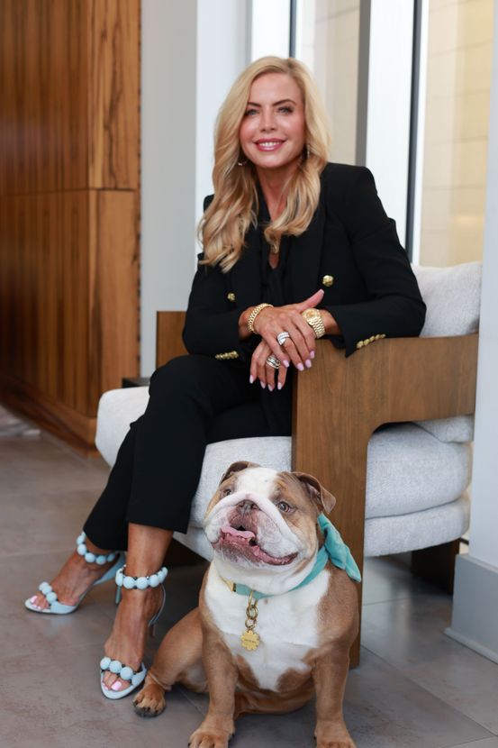 Woman seated in a chair with a bulldog at her feet in a bright indoor lobby