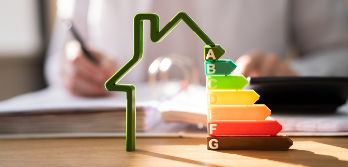 A person is sitting at a desk with a calculator and a stack of energy ratings