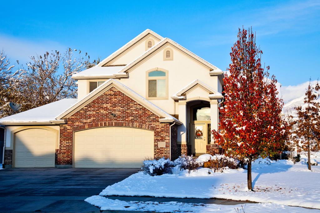 A snowy house with a tree in front of it