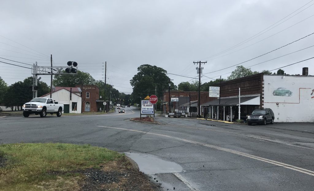 A white truck is driving down a street in a small town