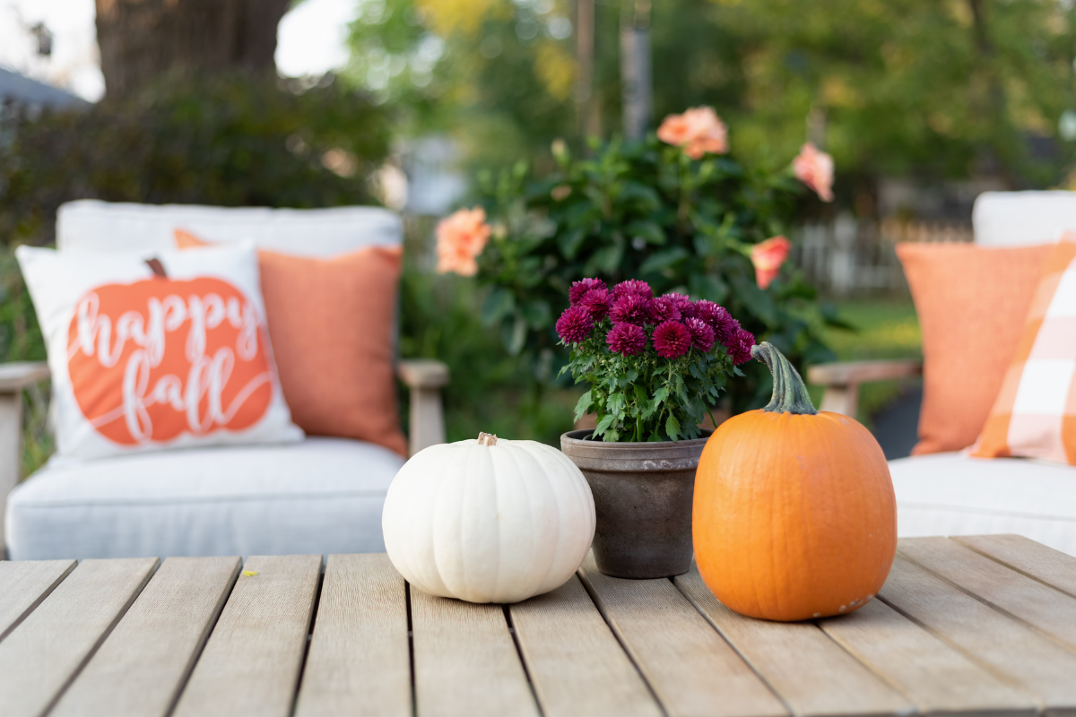A table with pumpkins and a pillow that says happy fall