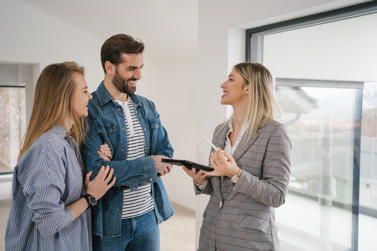 A woman is talking to a man and a woman in an empty room.