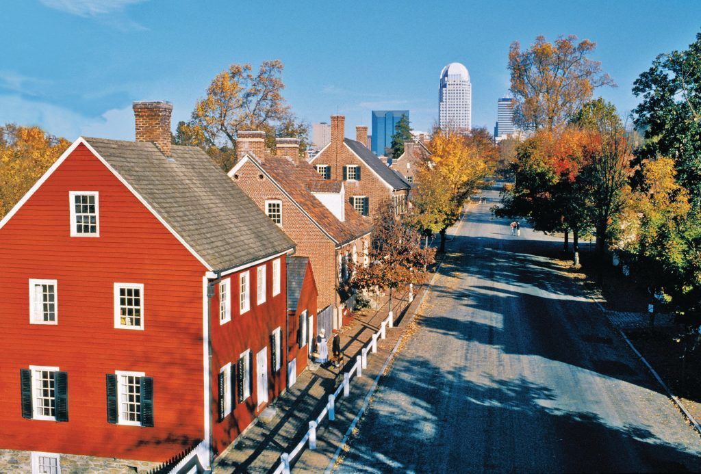 A red house with white shutters sits on the side of a road