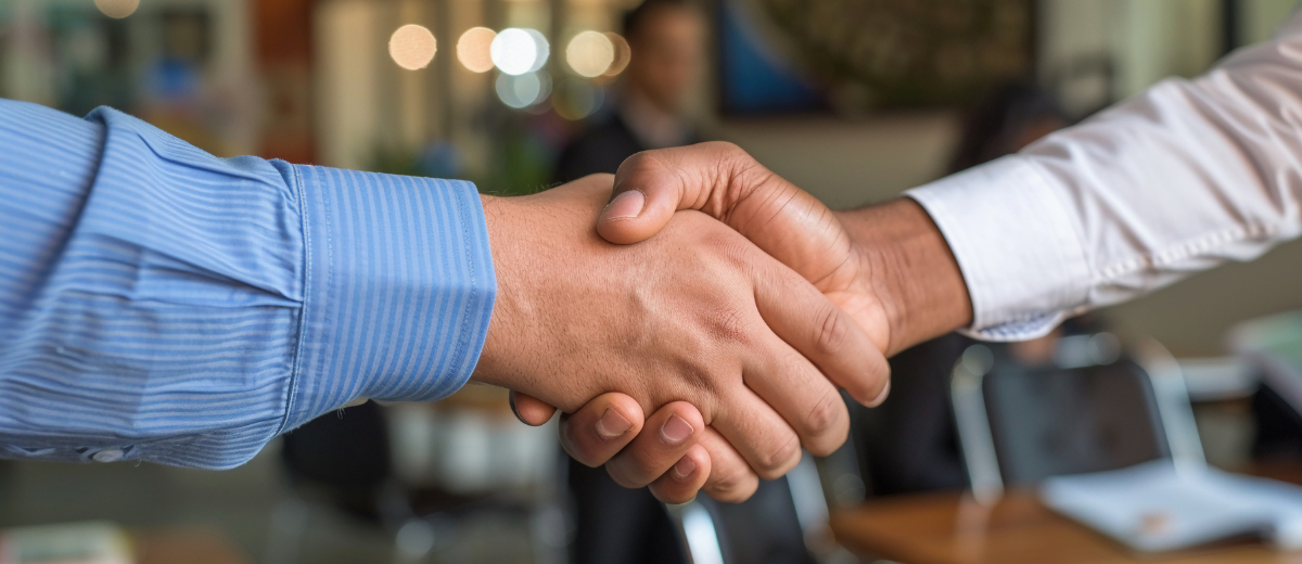 A man and a woman are shaking hands in an office.
