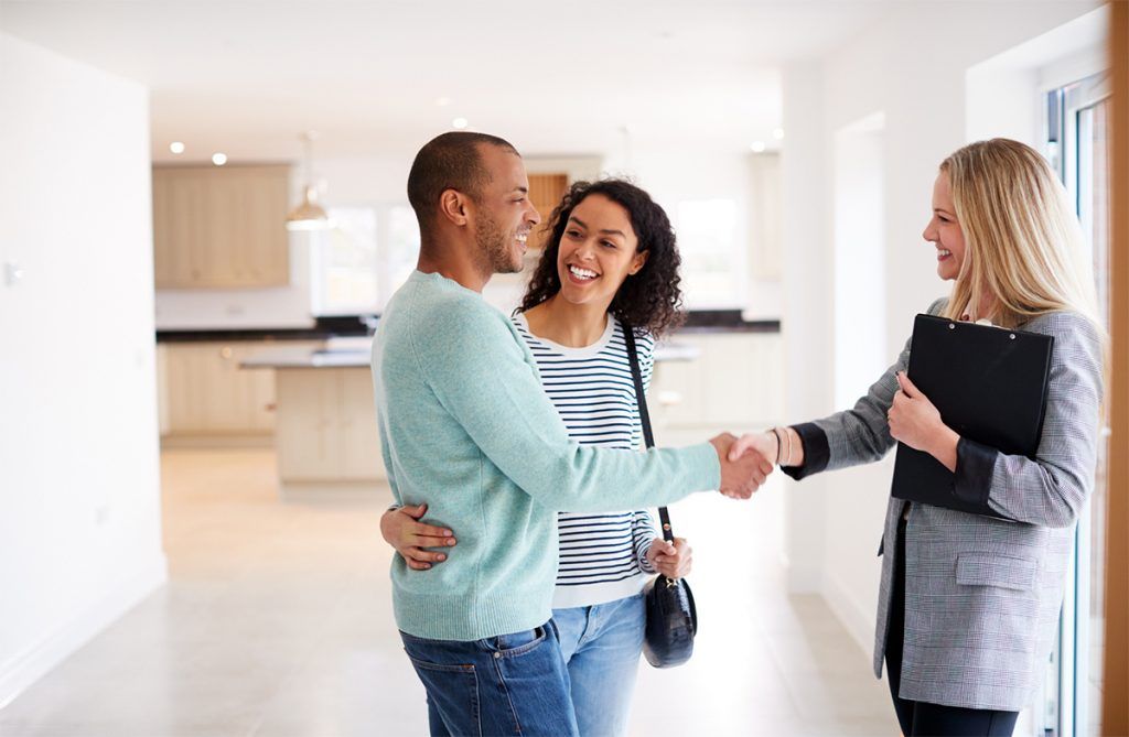Couple shaking hands with real estate agent after home purchase