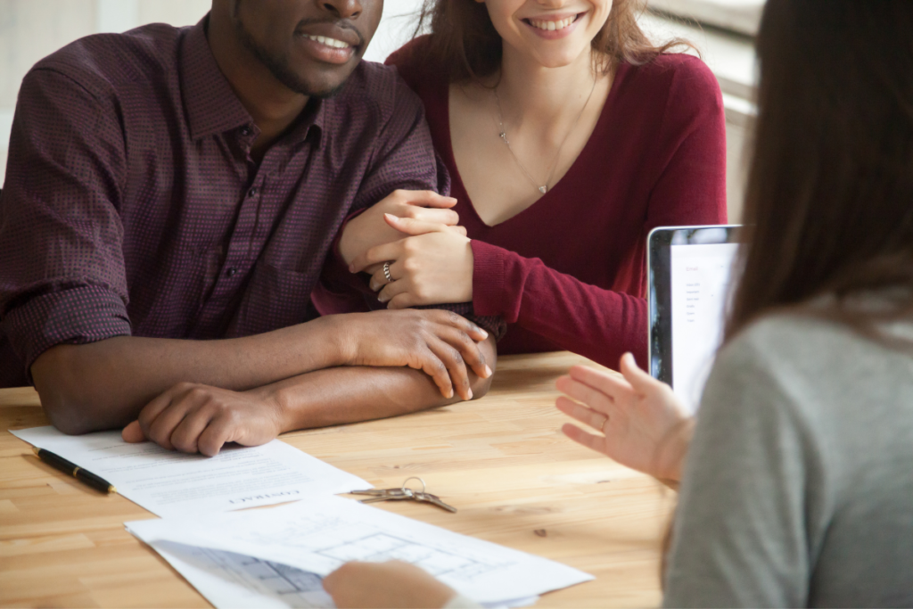 A man and a woman are sitting at a table with papers and a tablet.