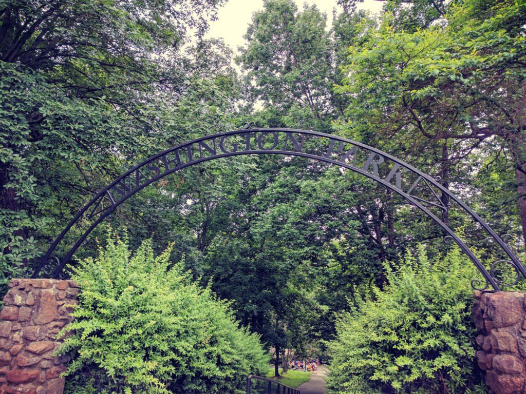 A stone archway leading to a park with trees and bushes