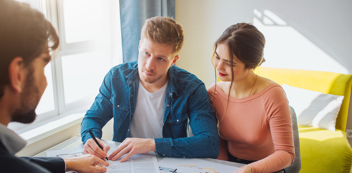 A man and a woman are sitting at a table looking at a blueprint.