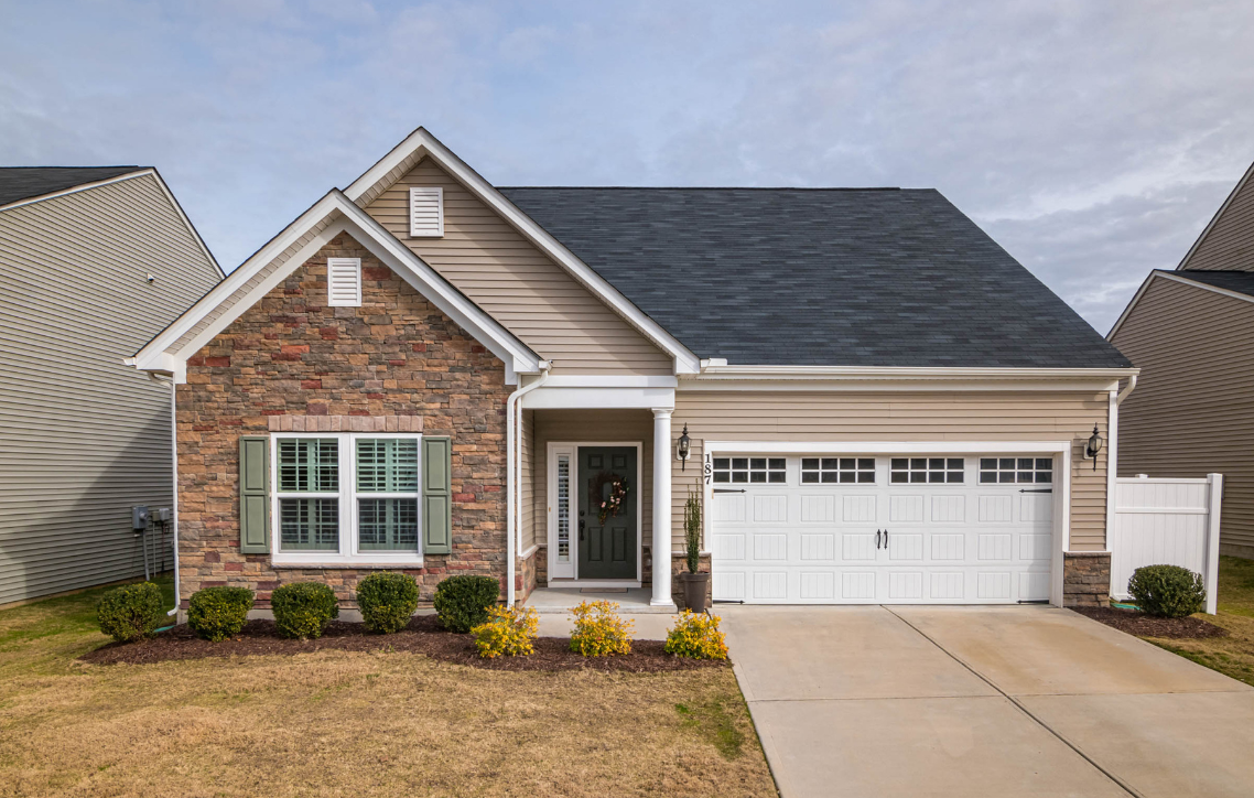 Single-story brick house with white trim, two-car garage, and a front lawn.