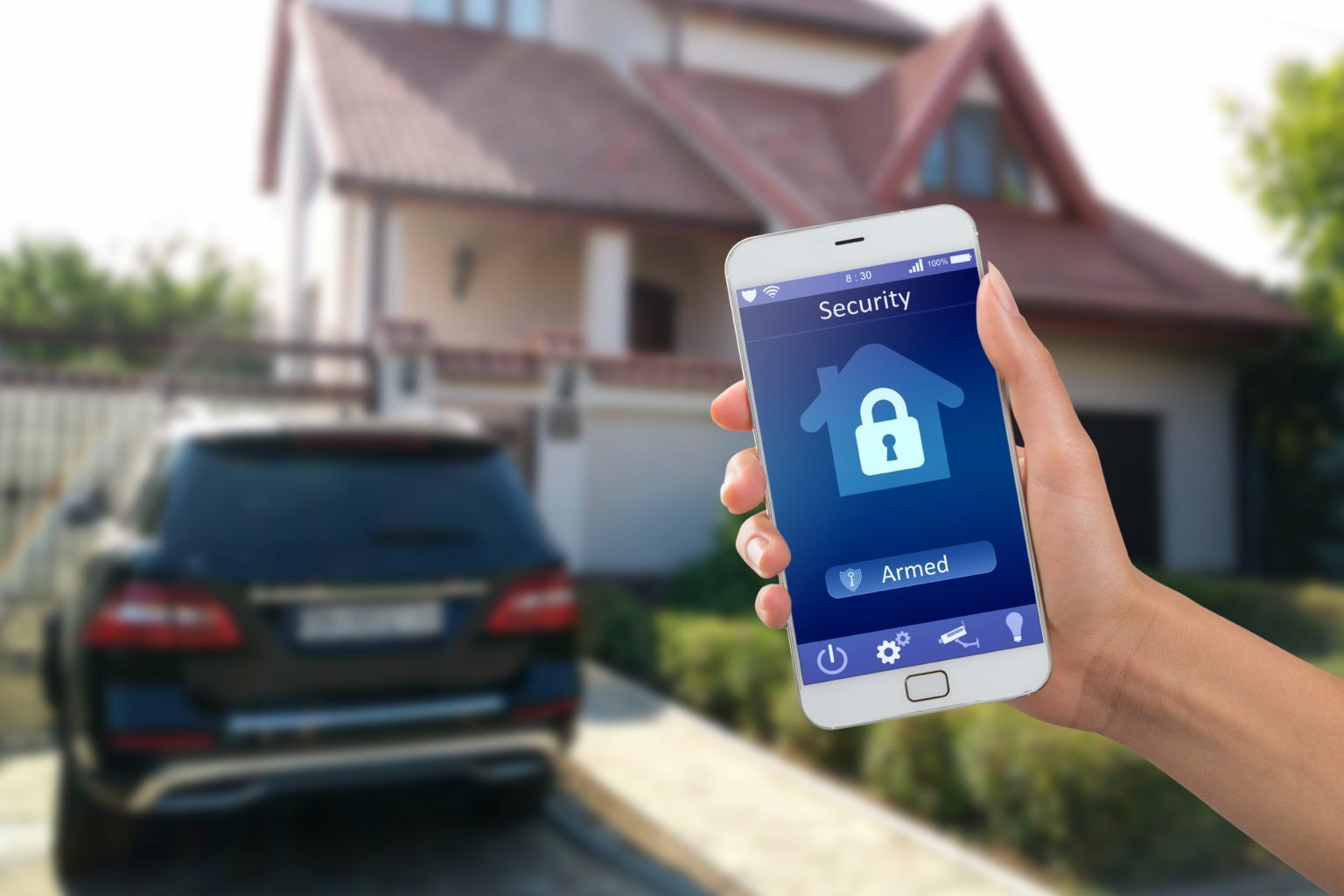 A person is holding a smart phone with a lock on it in front of a house