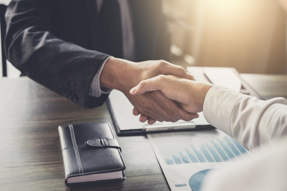 A man and a woman are shaking hands over a table.