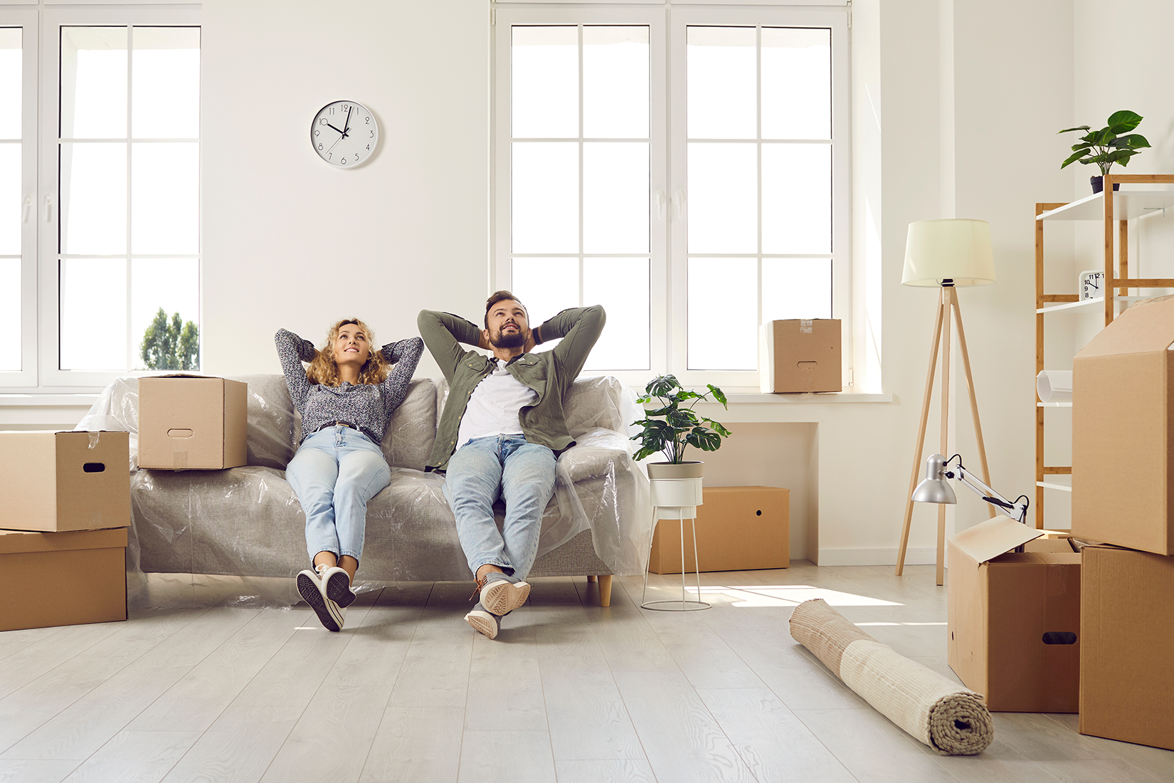 Happy couple relaxing in new home surrounded by moving boxes