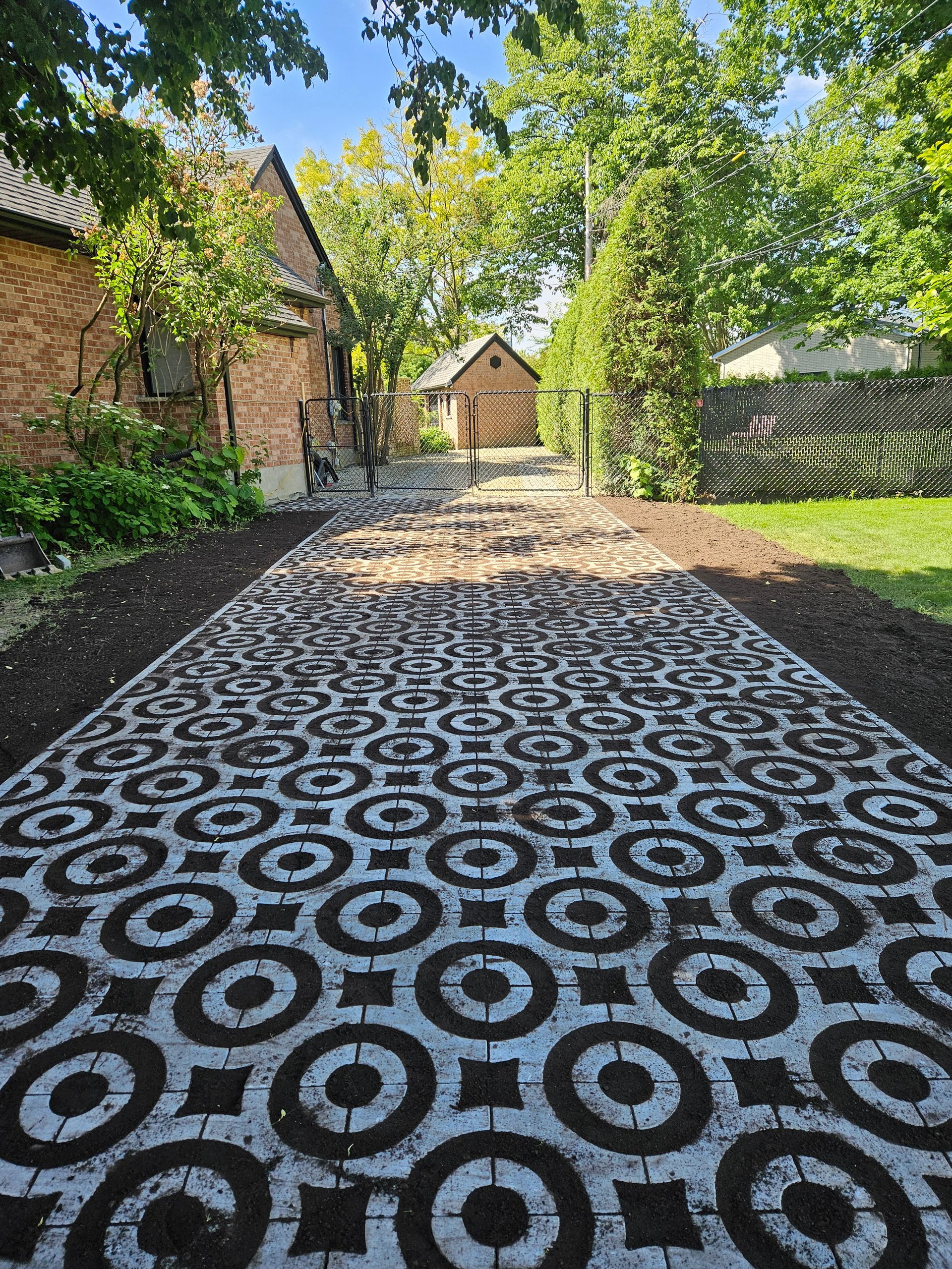 A black and white patterned driveway leading to a house.