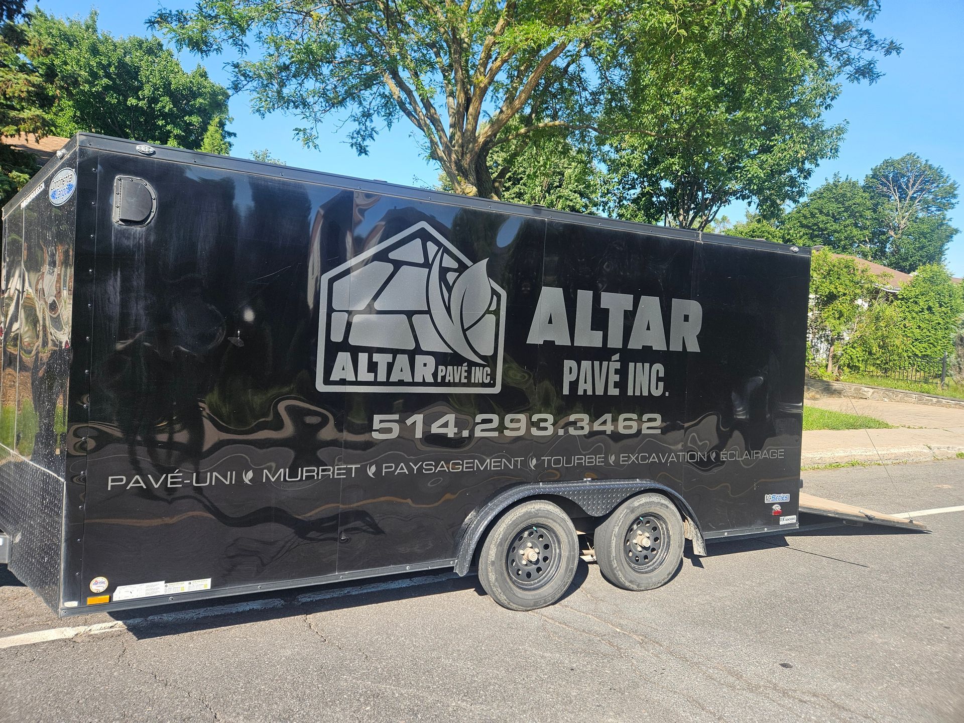 A black trailer for altar pavement is parked on the side of the road.