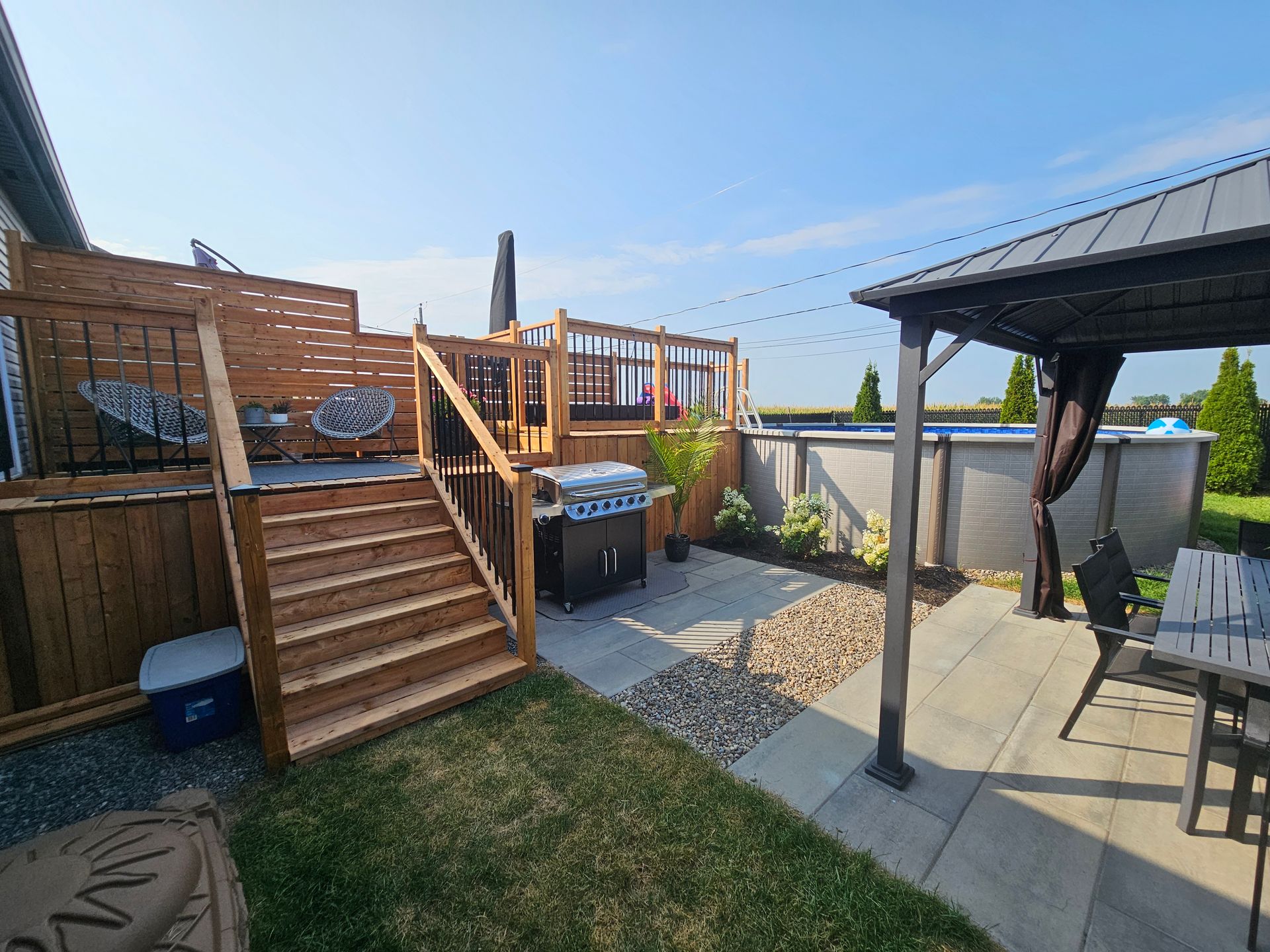 A wooden deck with stairs leading up to it and a gazebo in the backyard.