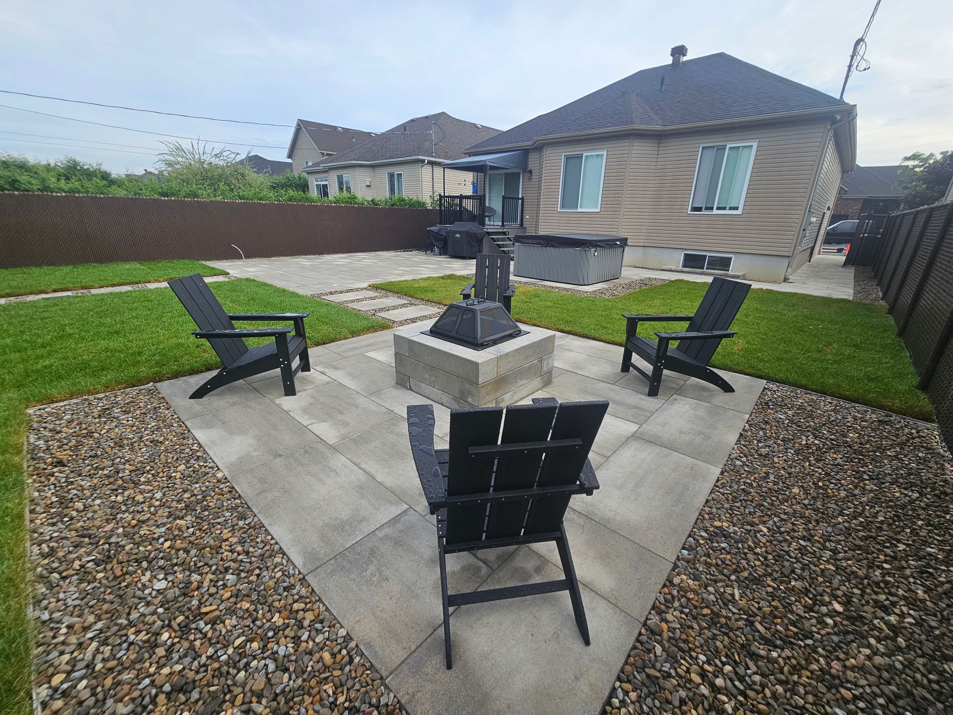 Three chairs are sitting around a fire pit in a backyard.