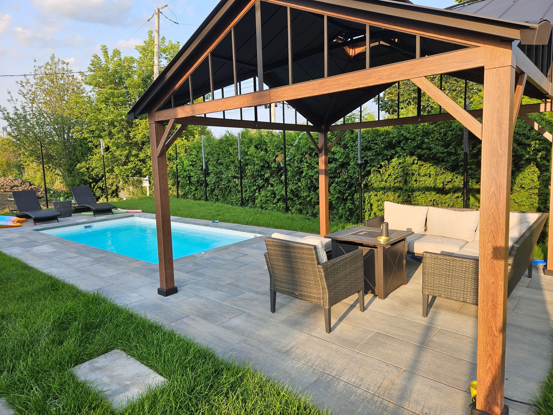 A patio with a pergola and a swimming pool in the background