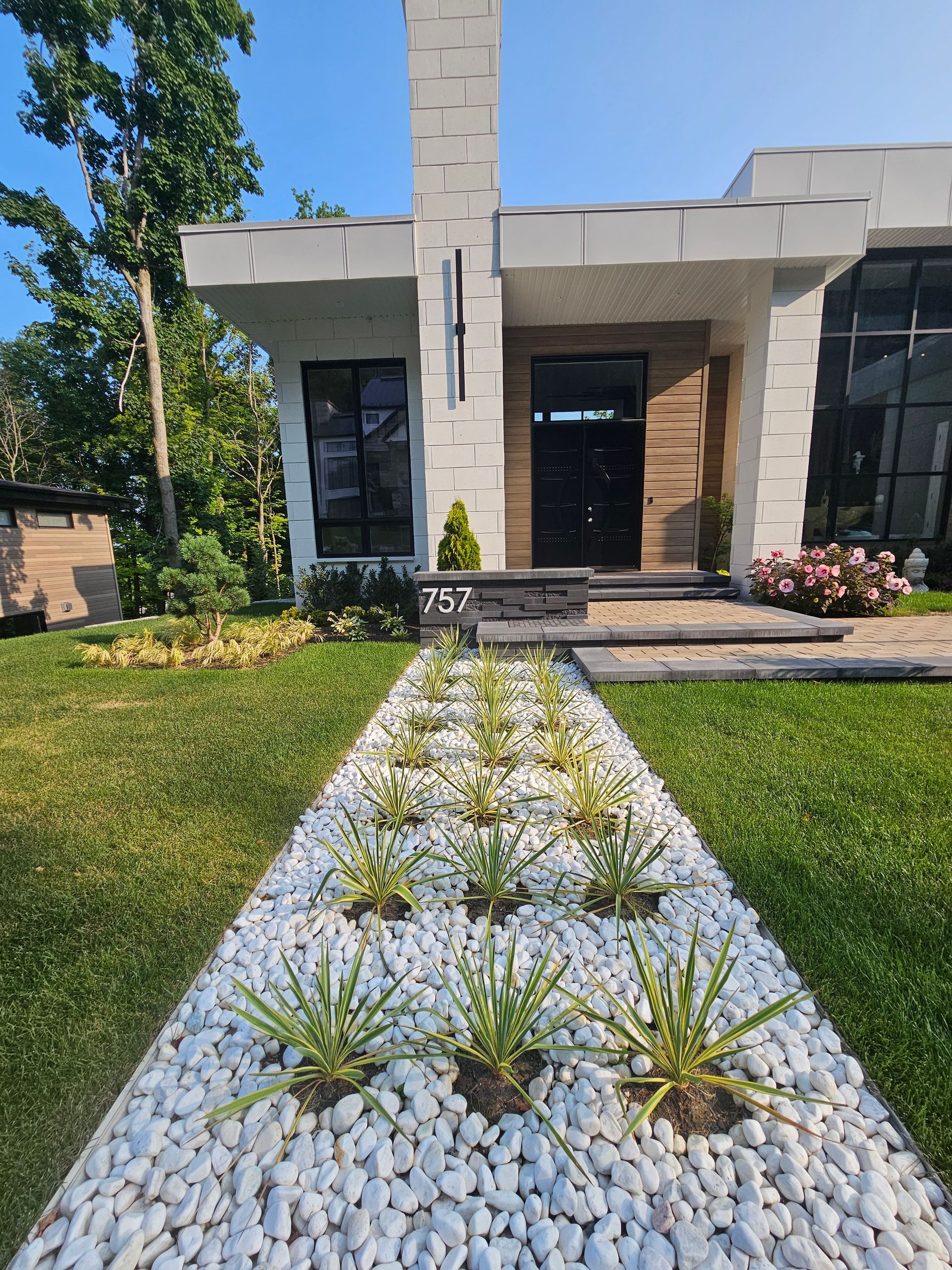 A house with a walkway lined with white rocks and plants in front of it.
