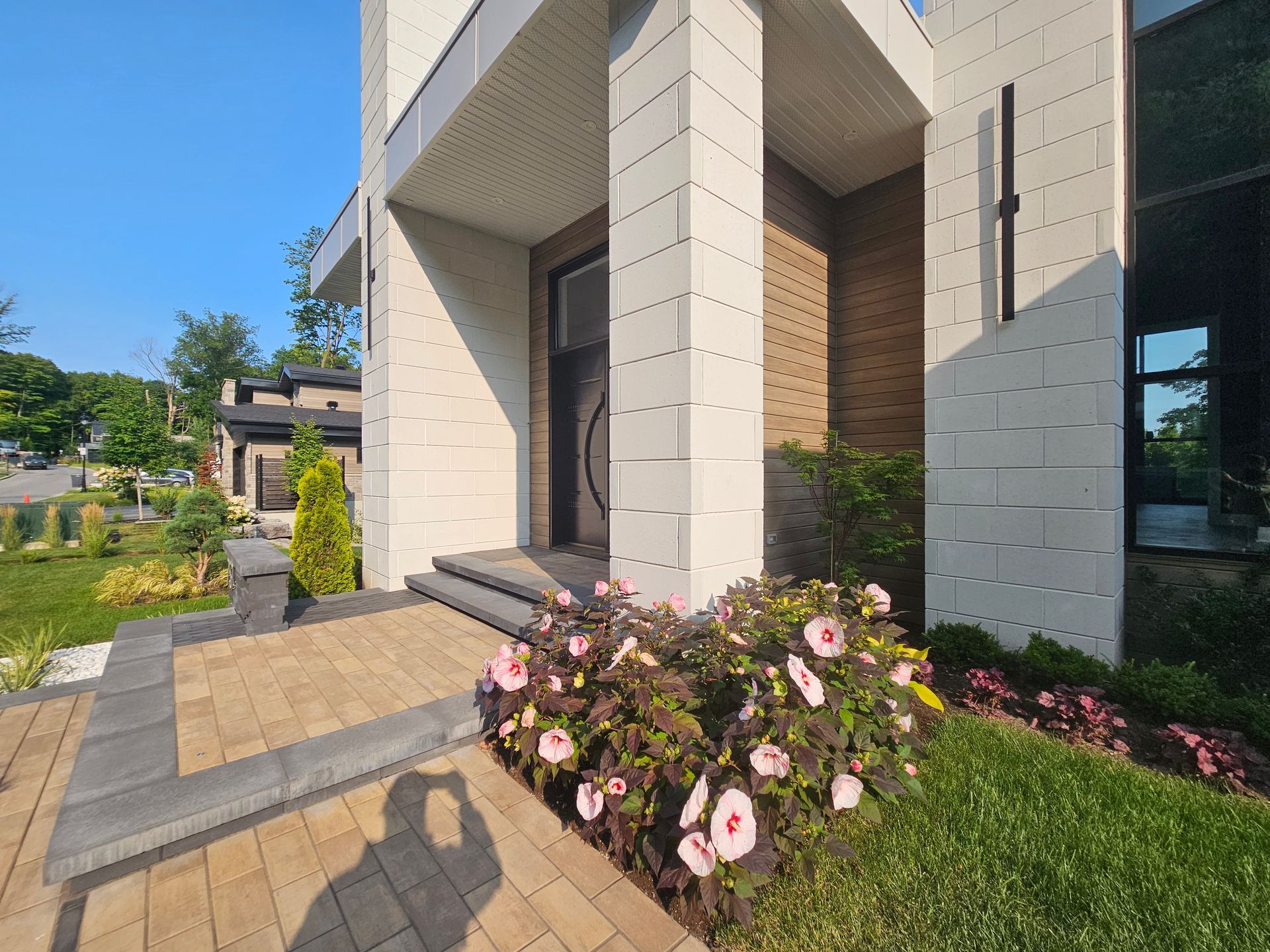 A house with a brick walkway and flowers in front of it.