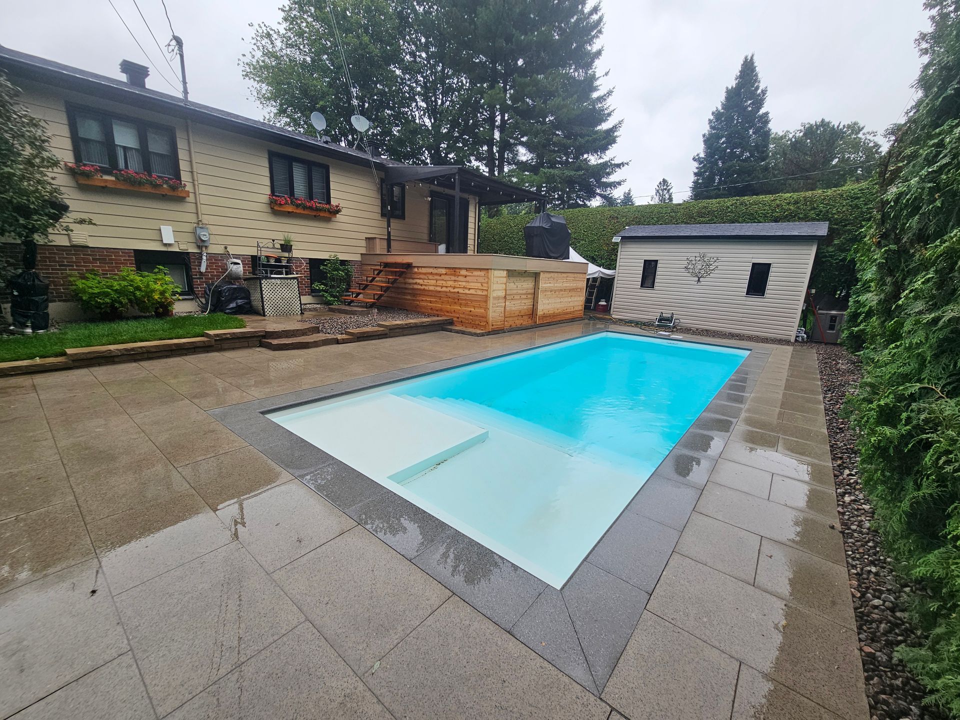 A large swimming pool is in the backyard of a house.