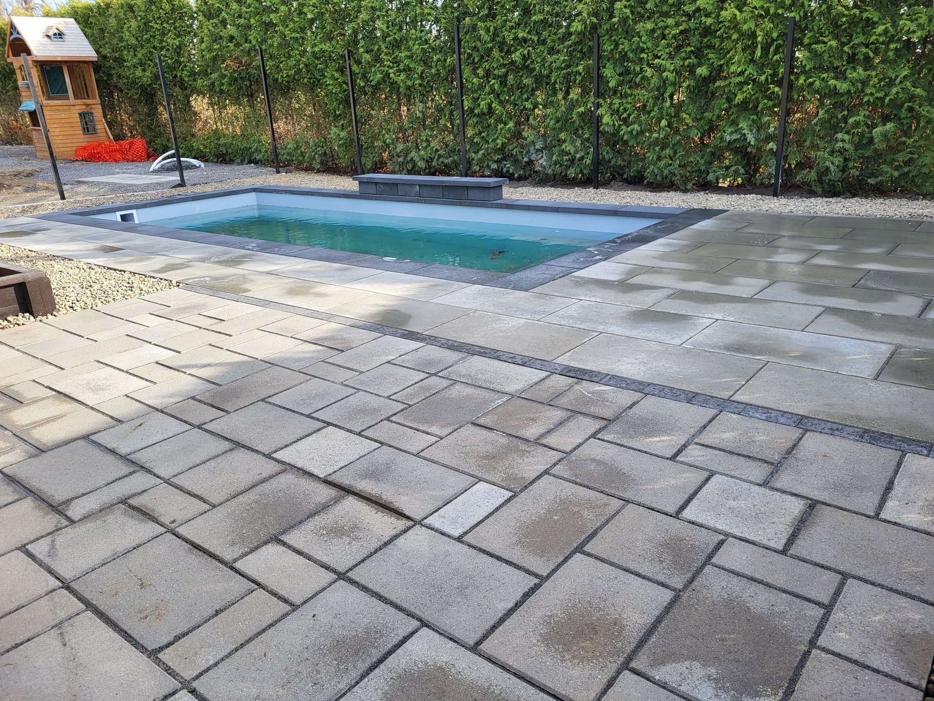 A small swimming pool is surrounded by a brick patio.