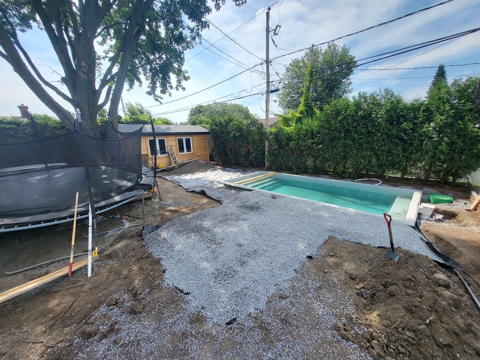 A swimming pool is being built in the backyard of a house.
