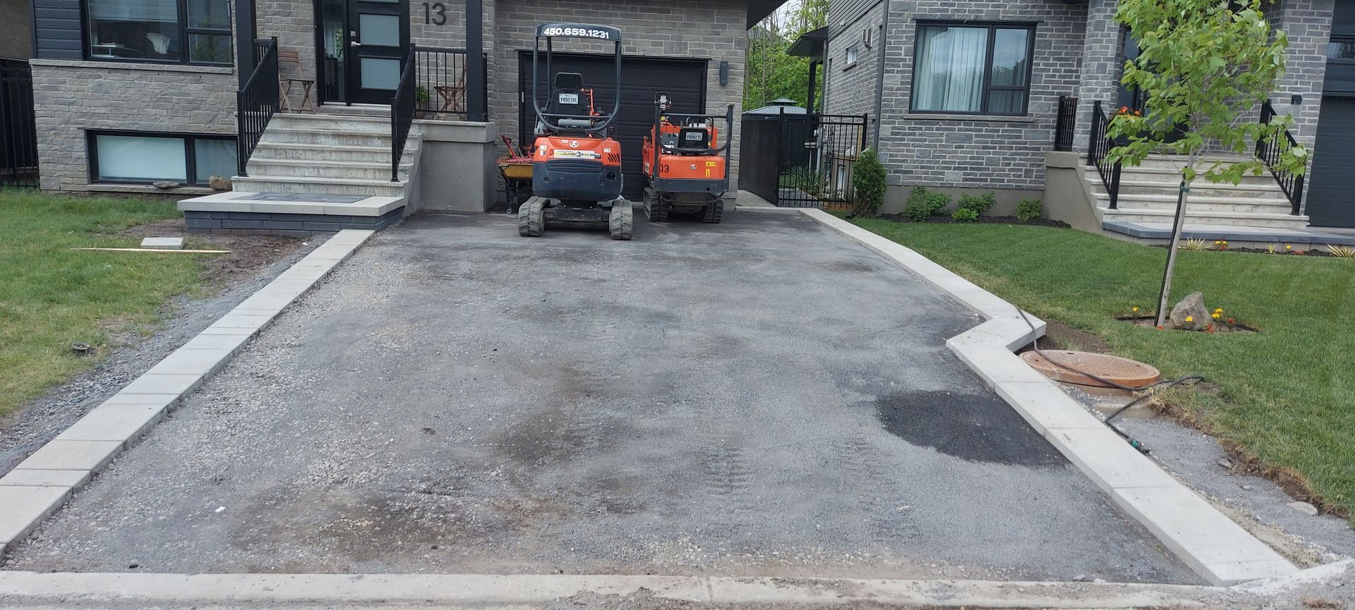 A gravel driveway is being built in front of a house.
