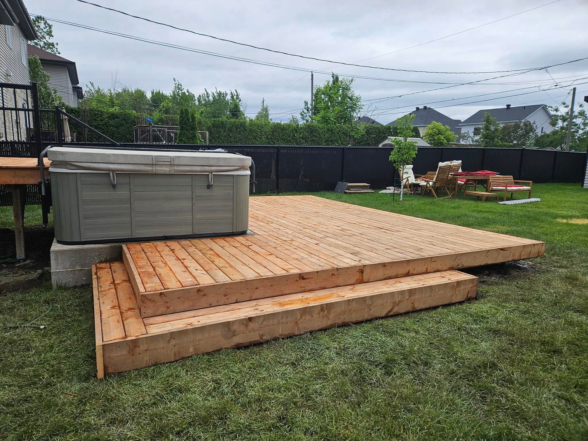 A hot tub is sitting on top of a wooden deck in a backyard.