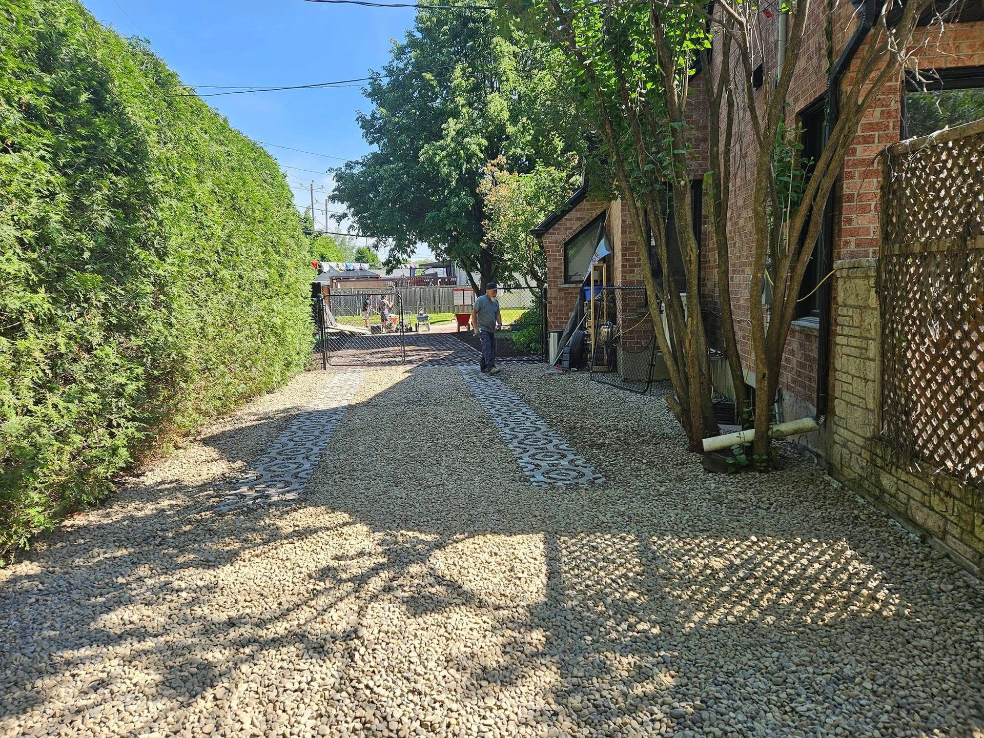 A gravel driveway leading to a brick building surrounded by trees and bushes.
