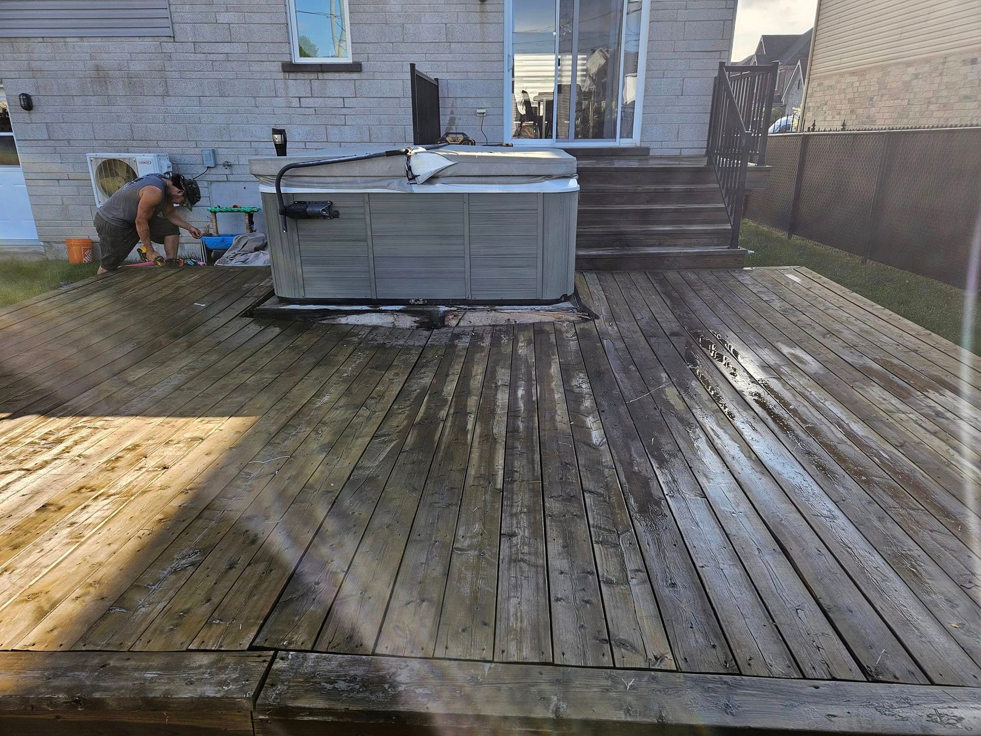 A man is standing on a wooden deck next to a hot tub.
