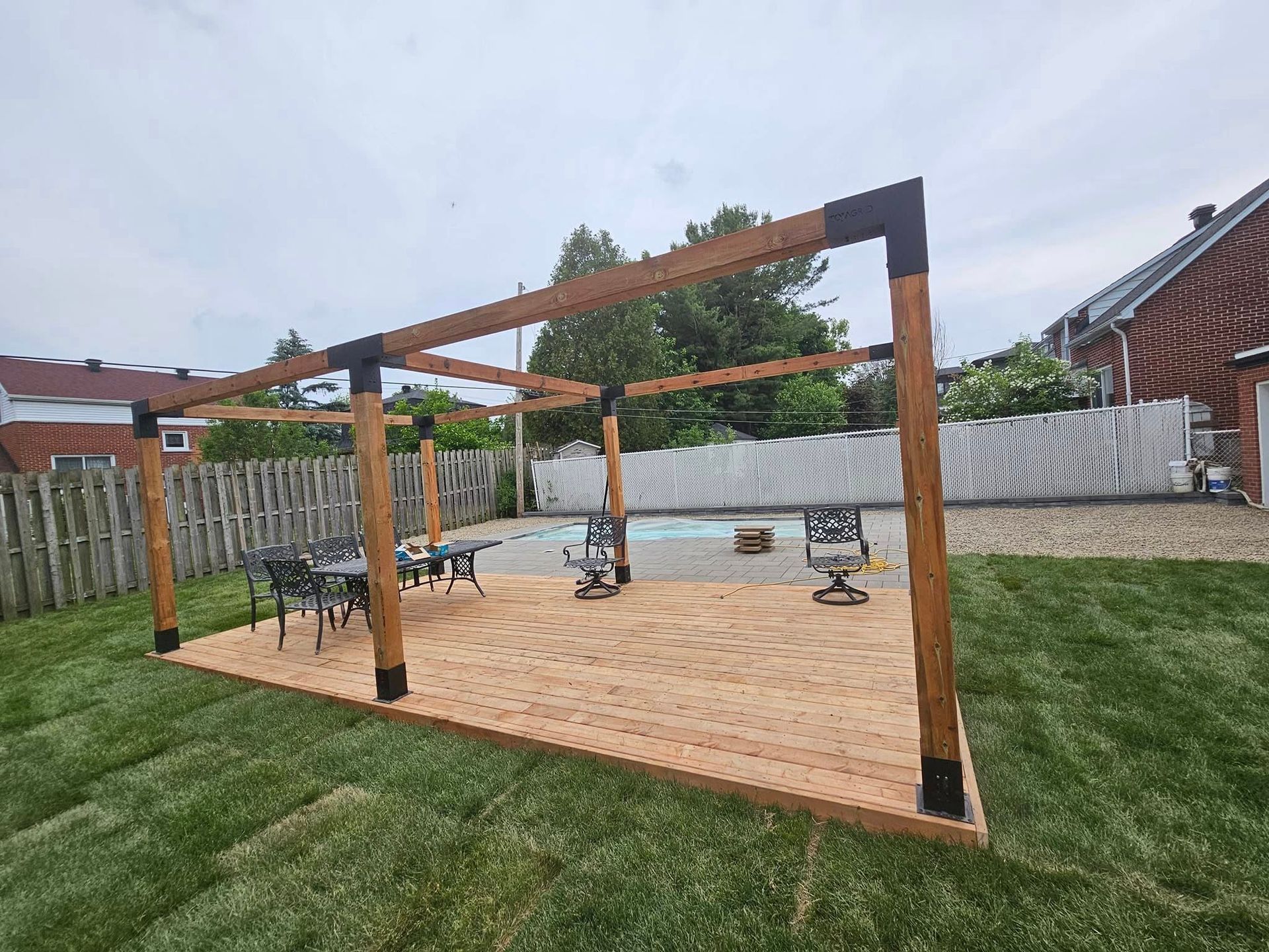 A wooden deck in a backyard next to a swimming pool.