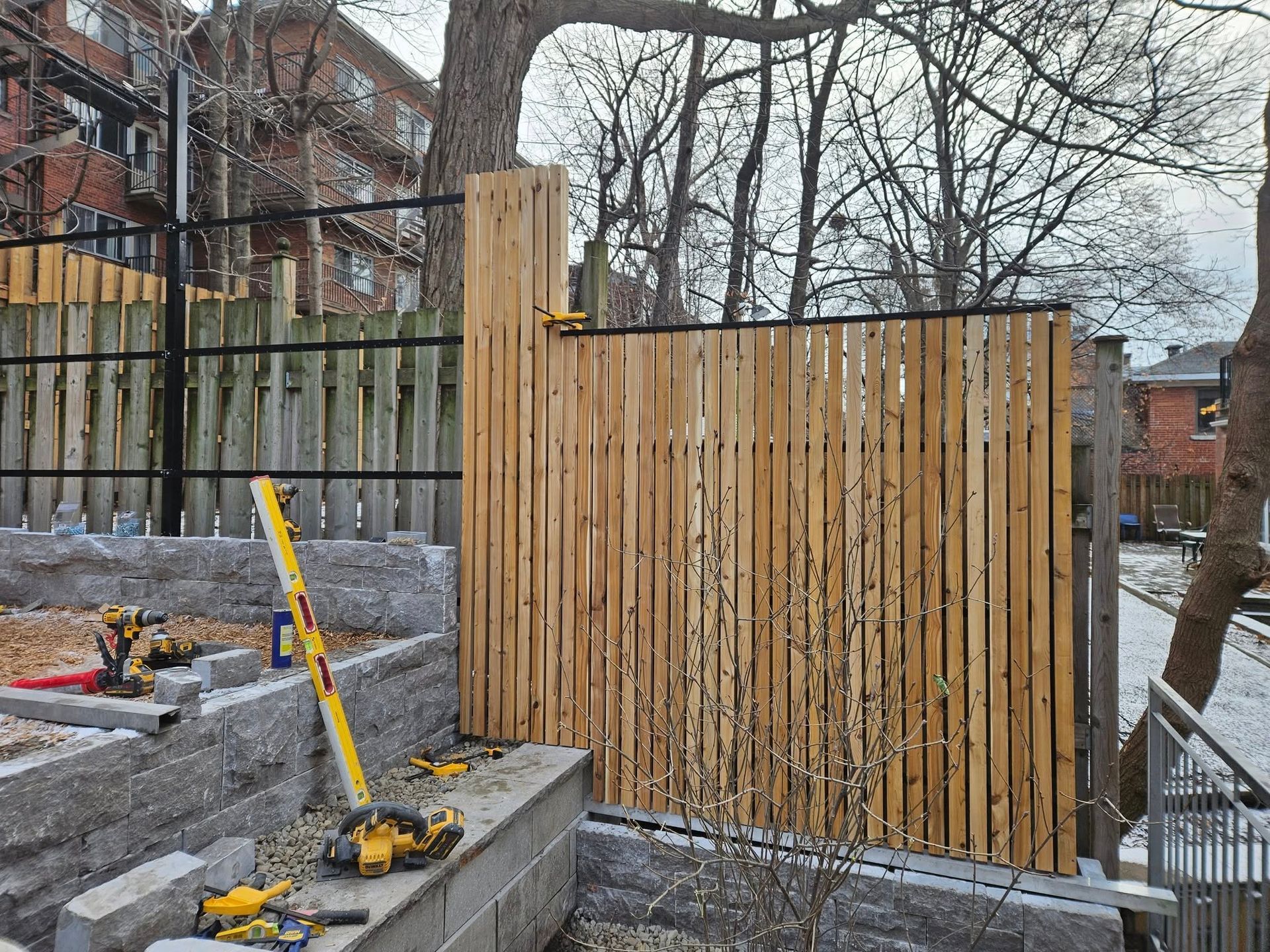 A wooden fence is being built in a backyard.