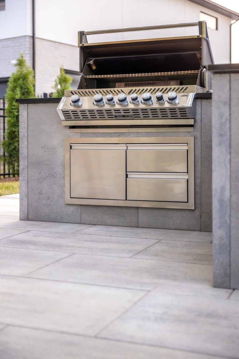 A stainless steel grill is built into a concrete wall.