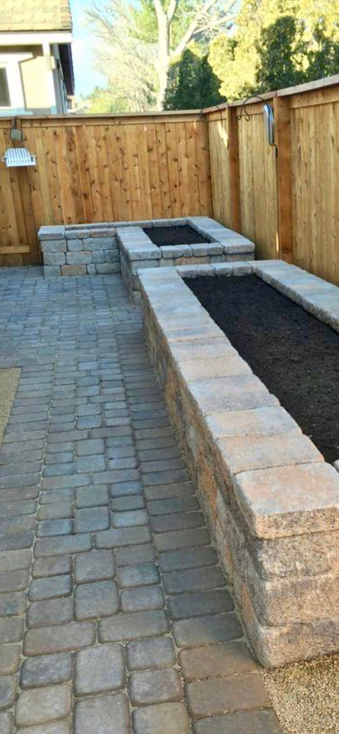 A brick patio with a fire pit and a wooden fence.