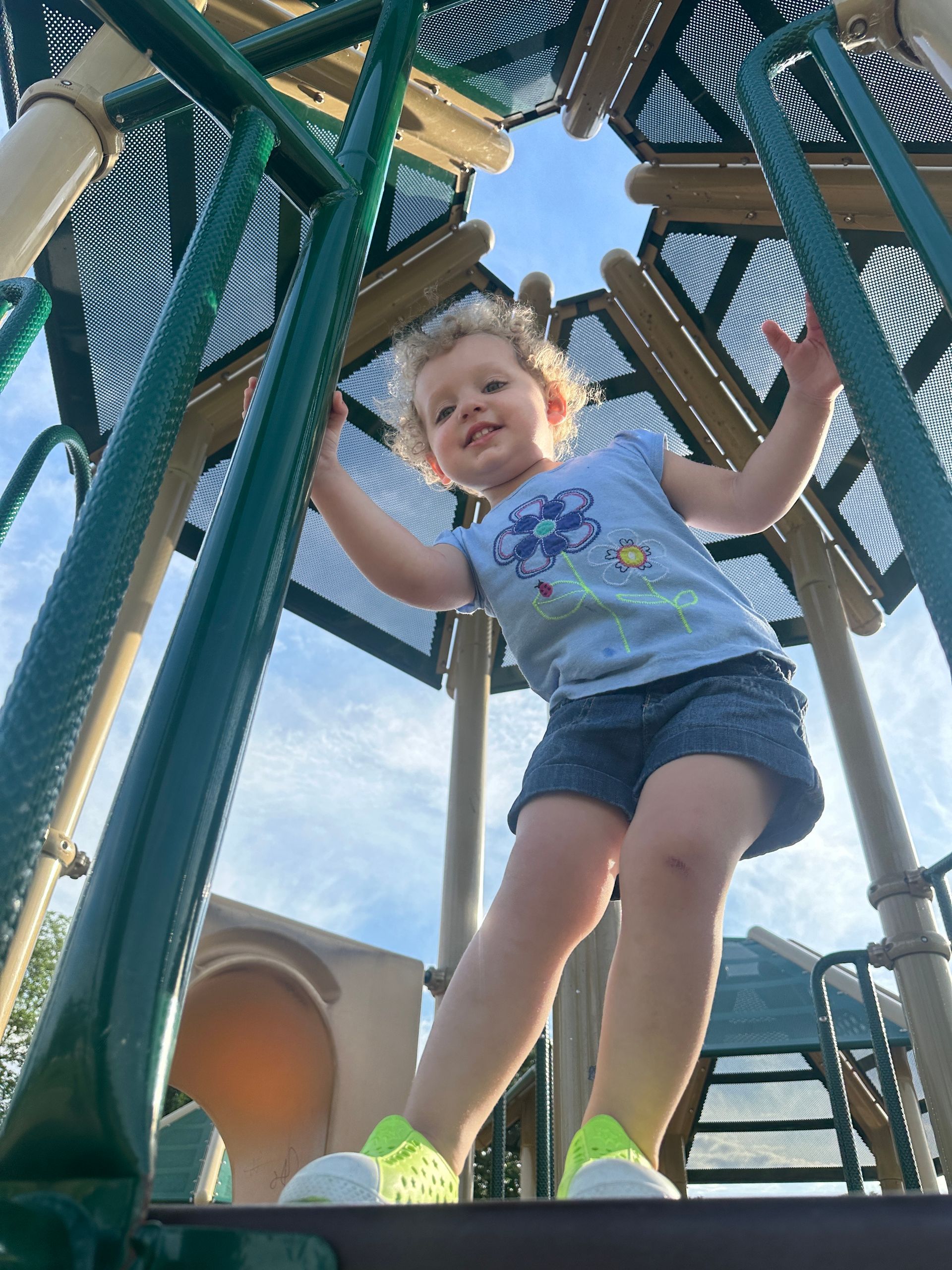 A little girl is climbing up a playground structure.