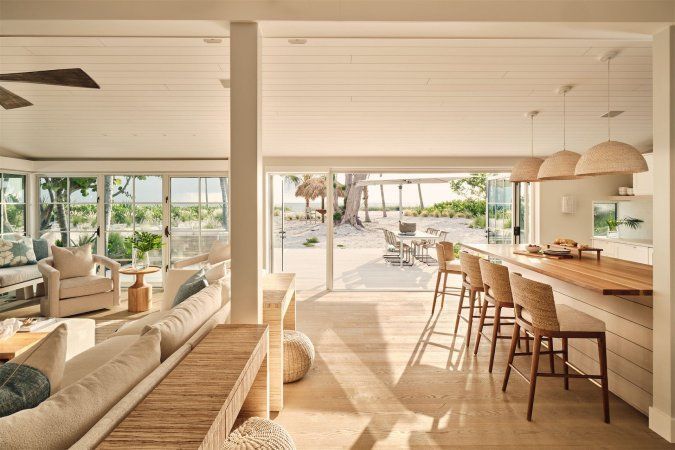 A living room with a couch and chairs and a kitchen with a table and chairs.