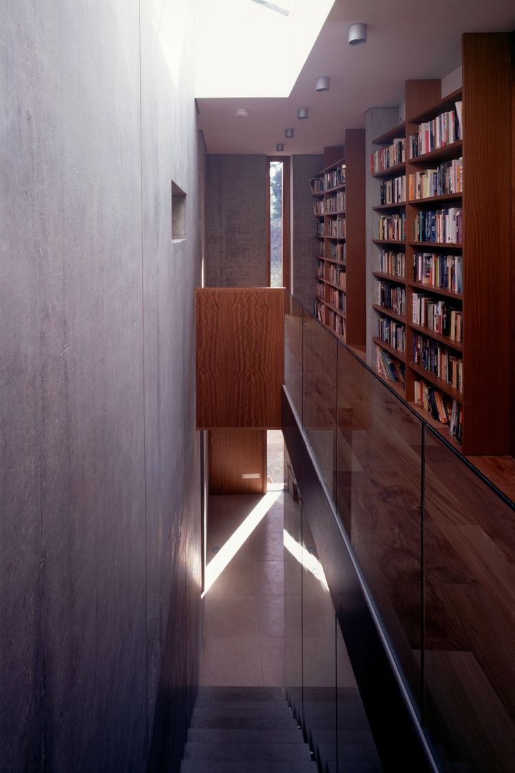a staircase with a glass railing and bookshelves