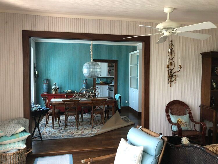 an outdated living room with a table and chairs and a ceiling fan