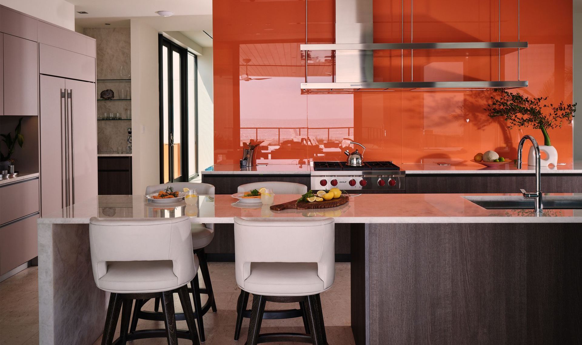 A kitchen with orange walls , stainless steel appliances , and a large island.