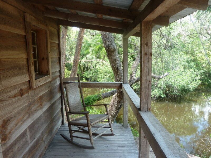 a rocking chair sits on a porch overlooking a body of water