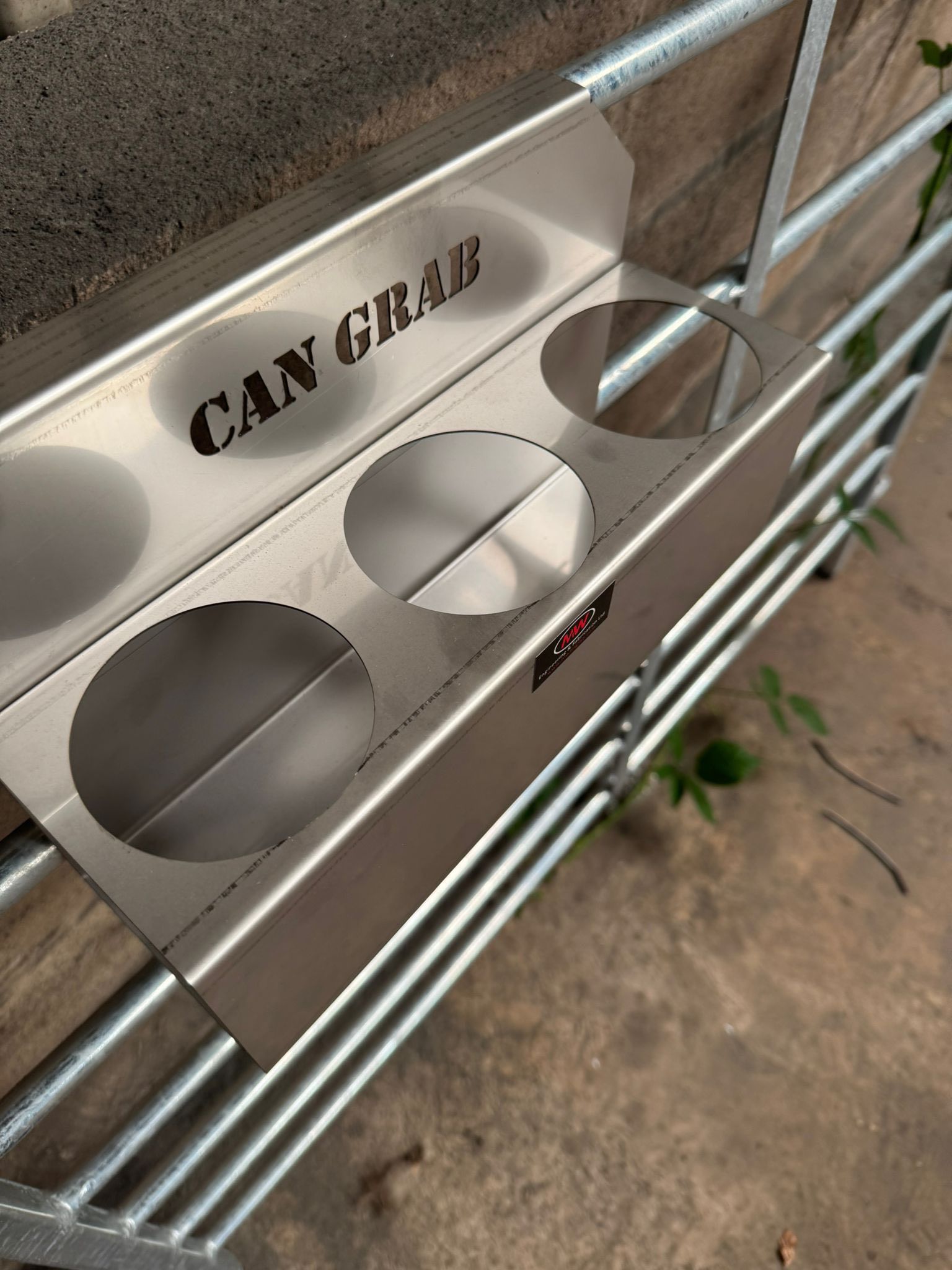 MW Engineering Can Grab for holding various sized cans looped over a metal fence