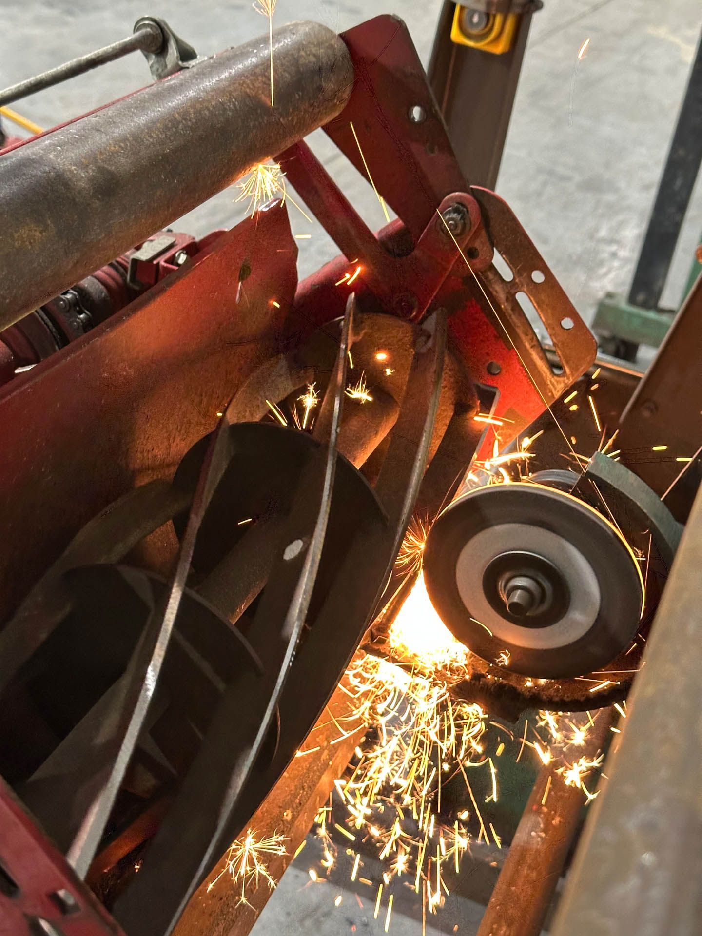 A machine is sharpening a REEL Mower and with metal with sparks coming out of it