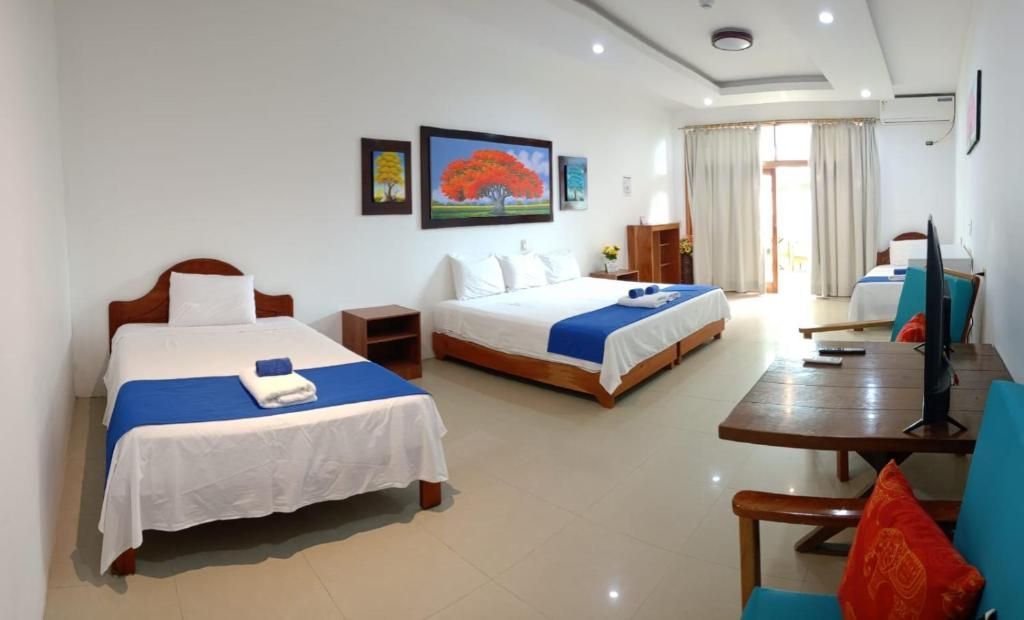 Una habitación de hotel con tres camas, un sofá, un escritorio y un televisor.