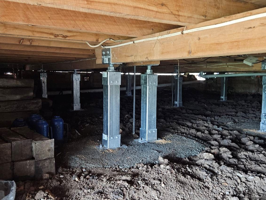 Concrete supports under an elevated wooden structure over gravel ground