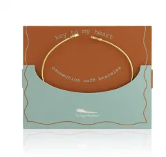 Gold cuff bracelet on a gift card, brown and teal.